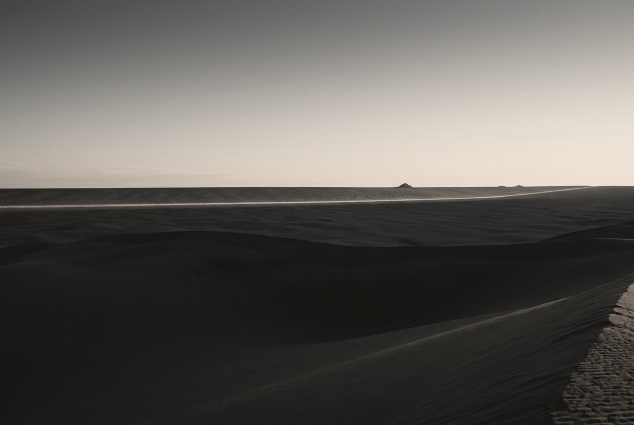 Horizonte de dunas escuras com uma linha de luz